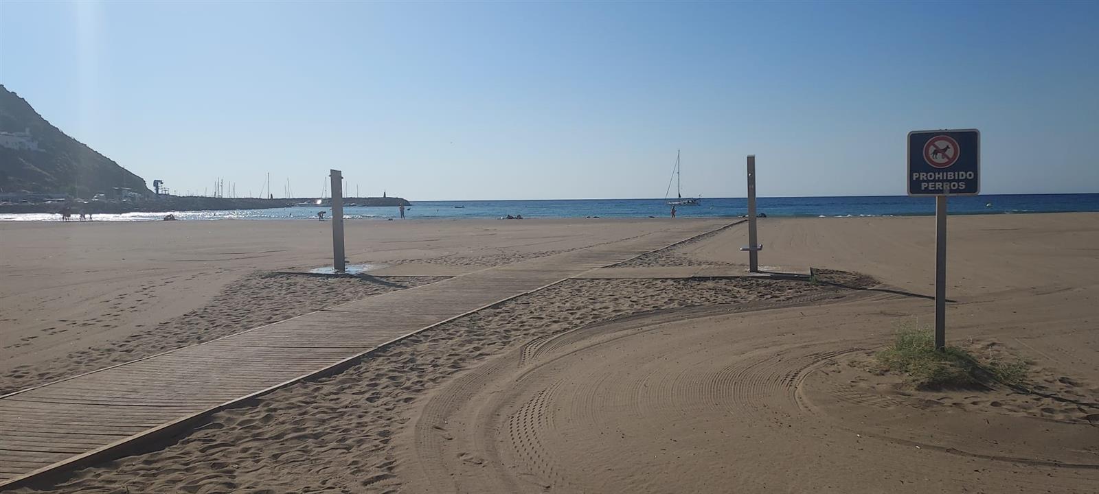 Pasarela de madera accesible en la Playa de San José con el puerto y el mar al fondo en un día tranquilo