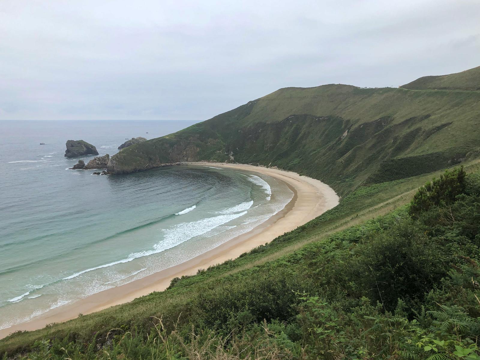 Playa de Torimbia desde la parte alta del sendero, mostrando la forma de concha y la arena dorada