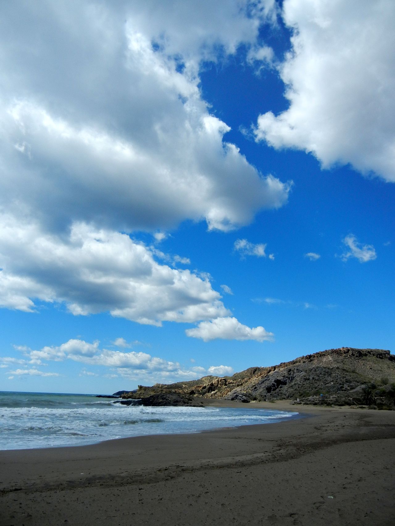 Playa de Percheles desde la orilla, arena oscura y cielo abierto, Mazarrón, Murcia