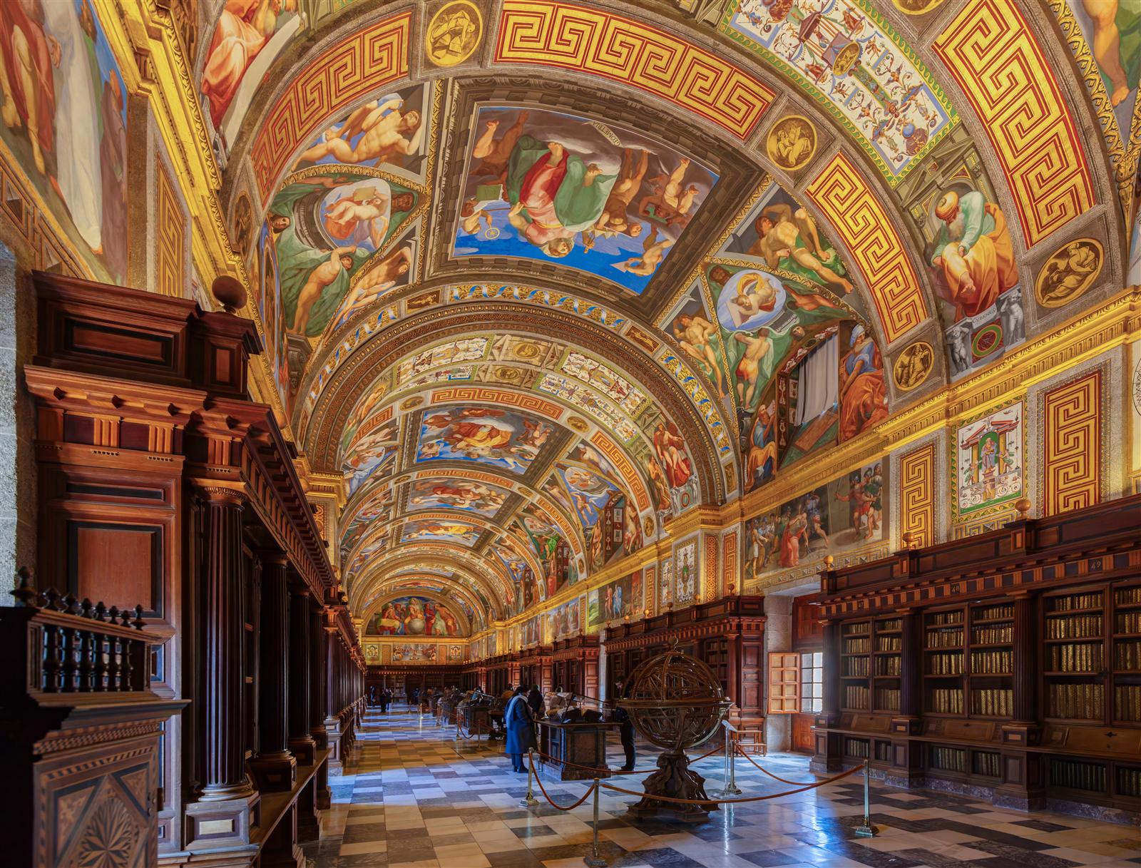 Interior de la Biblioteca Real del Monasterio de El Escorial, con frescos en el techo y estanterías históricas