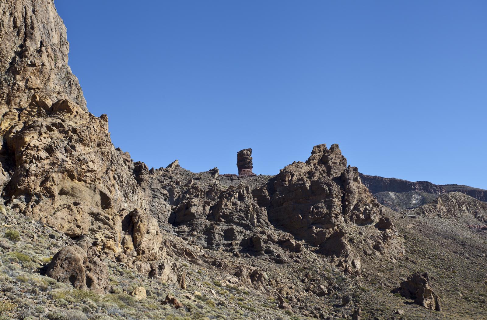El Roque Cinchado visto a distancia entre otras formaciones, con la ladera del Teide al fondo