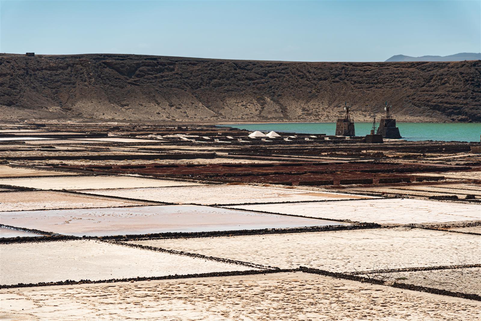 Vista panorámica de las Salinas de Janubio en Yaiza, Lanzarote, con estanques de sal rosada, barra de arena volcánica negra y el Atlántico al fondo