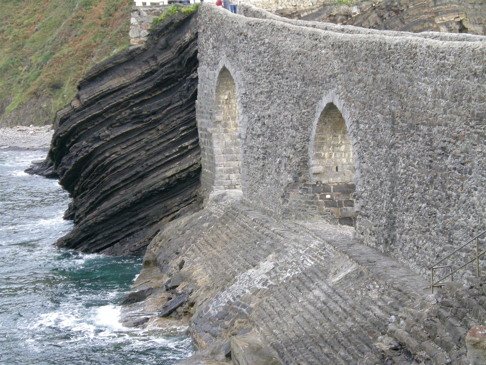 Detalle de los arcos de piedra del puente de acceso, con la roca estratificada