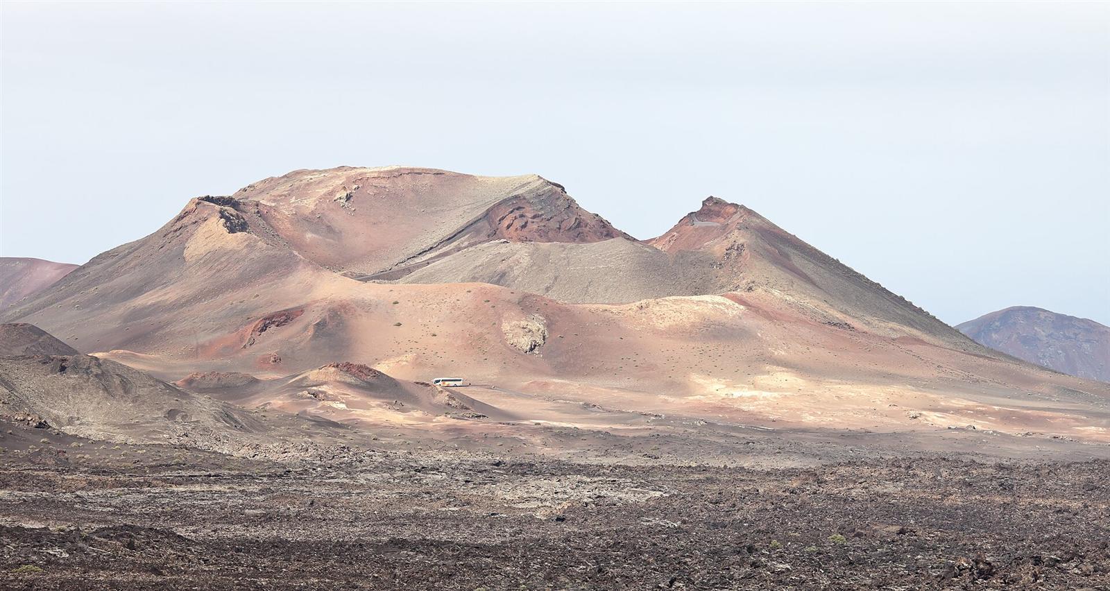 El paisaje volcánico abierto de Timanfaya, con varios conos y el campo de lava en primer plano
