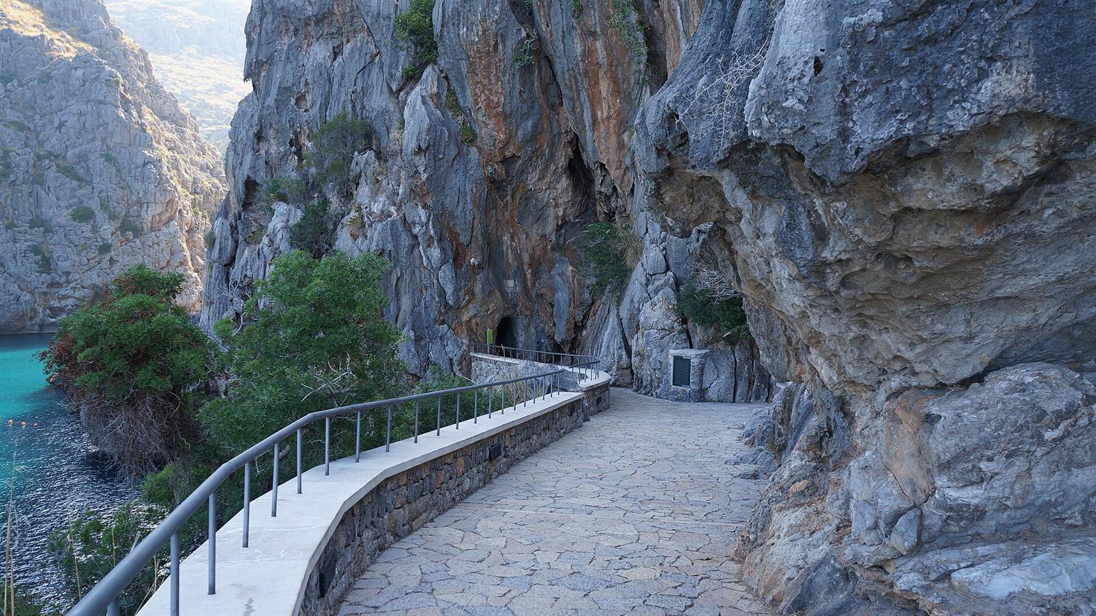 El camino peatonal y la entrada al túnel junto al agua turquesa de Sa Calobra