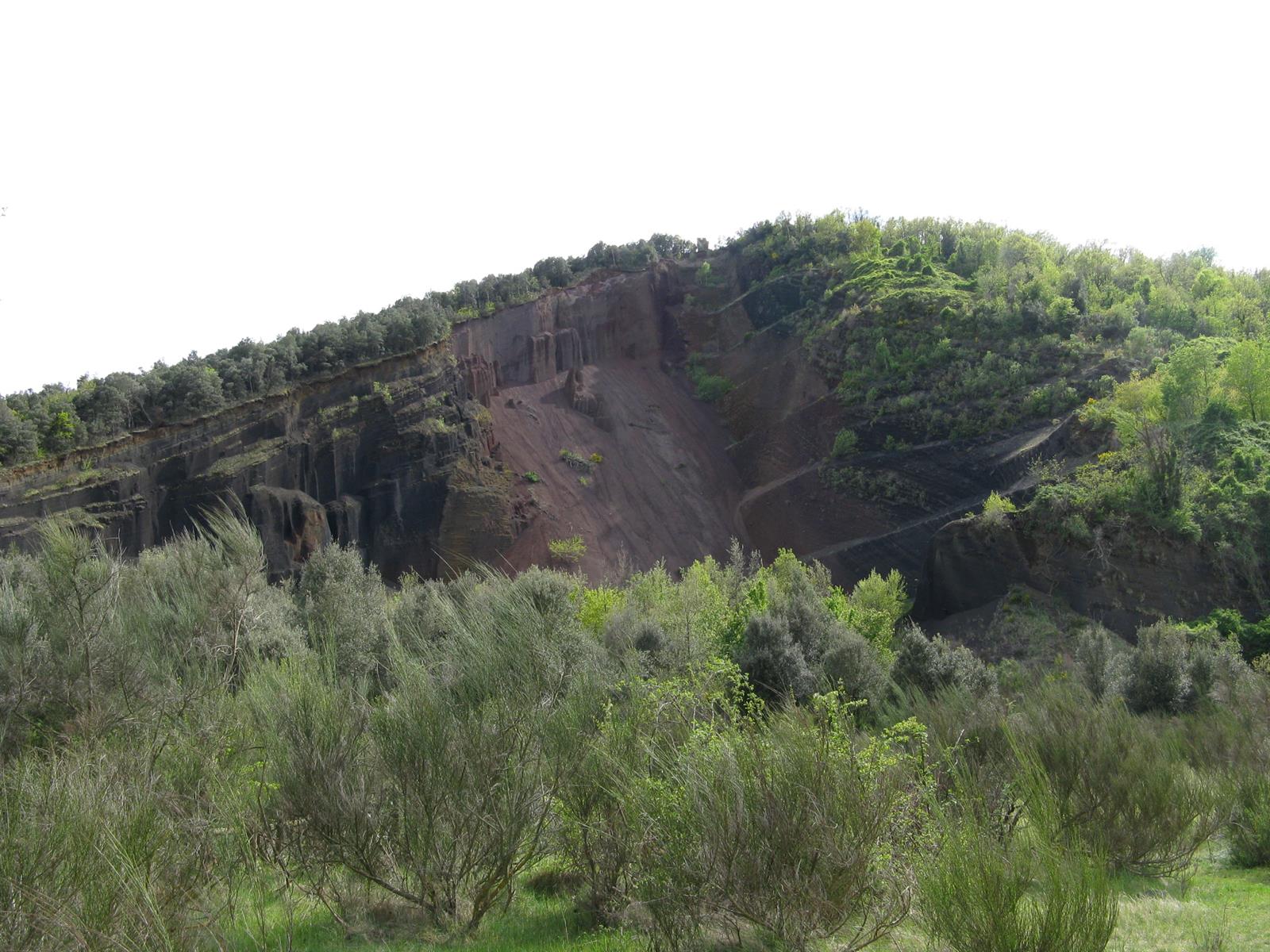 Perfil exterior del Volcán Croscat visto desde la distancia: silueta volcánica con el corte rojizo de la gredera visible en el flanco, La Garrotxa