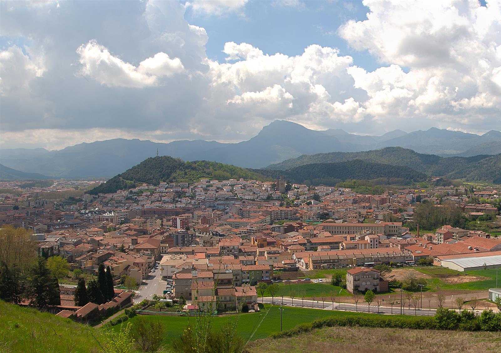 Panorámica de Olot desde el mirador del Volcán Montsacopa: la ciudad extendida en la llanura volcánica rodeada de volcanes y montañas de La Garrotxa