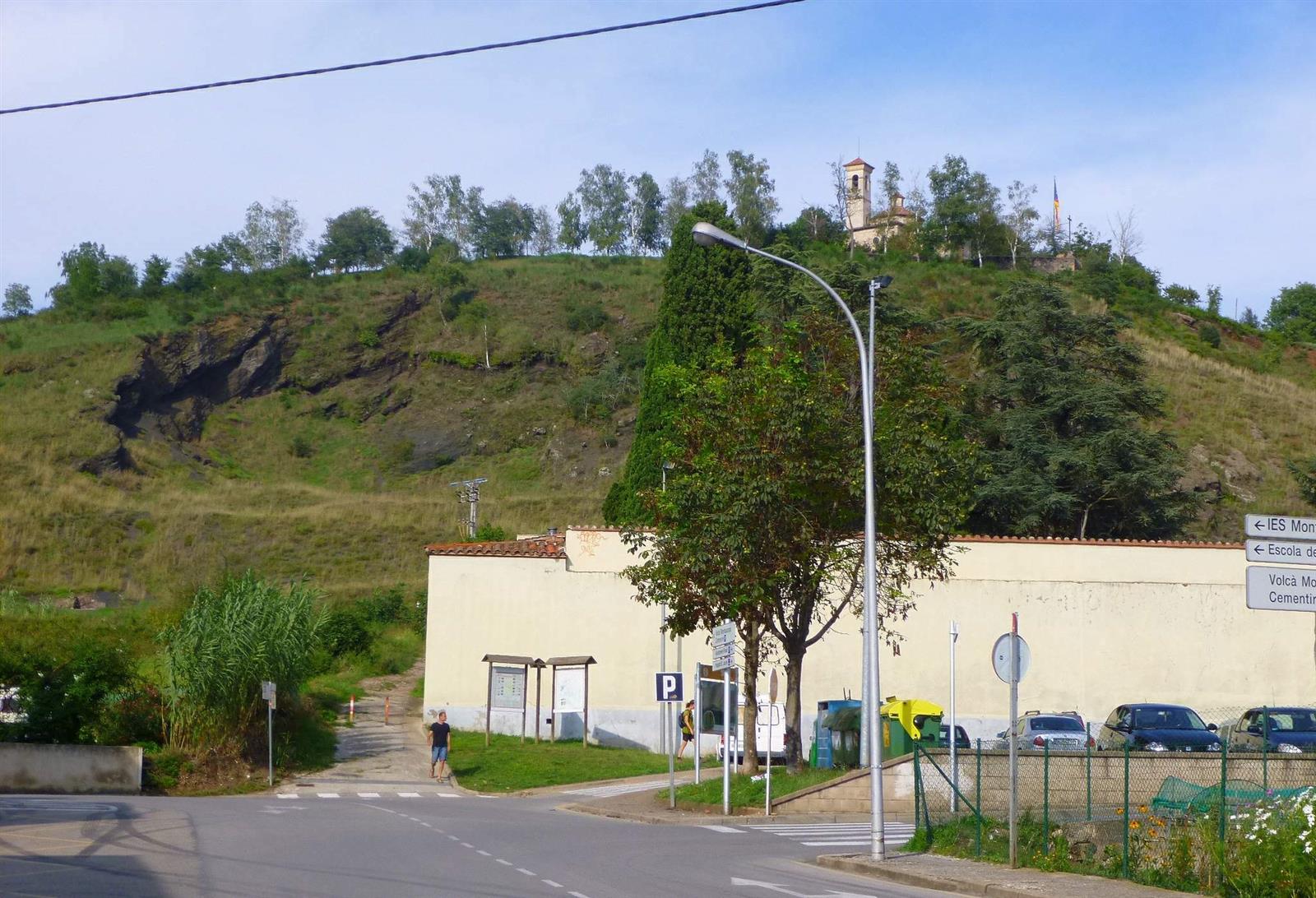 Vista del Volcán Montsacopa desde la calle en Olot: el cono volcánico con la iglesia de Sant Francesc en la cima y el acceso al pie del volcán