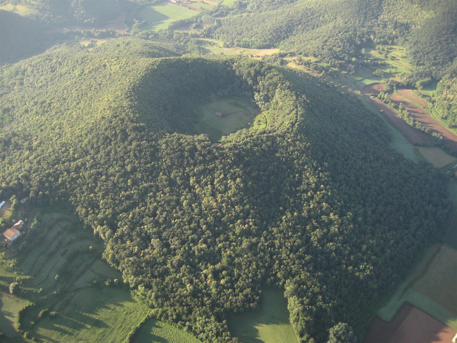 Vista exterior del Volcán de Santa Margarida con el cráter cubierto de bosque y vegetación volcánica en La Garrotxa
